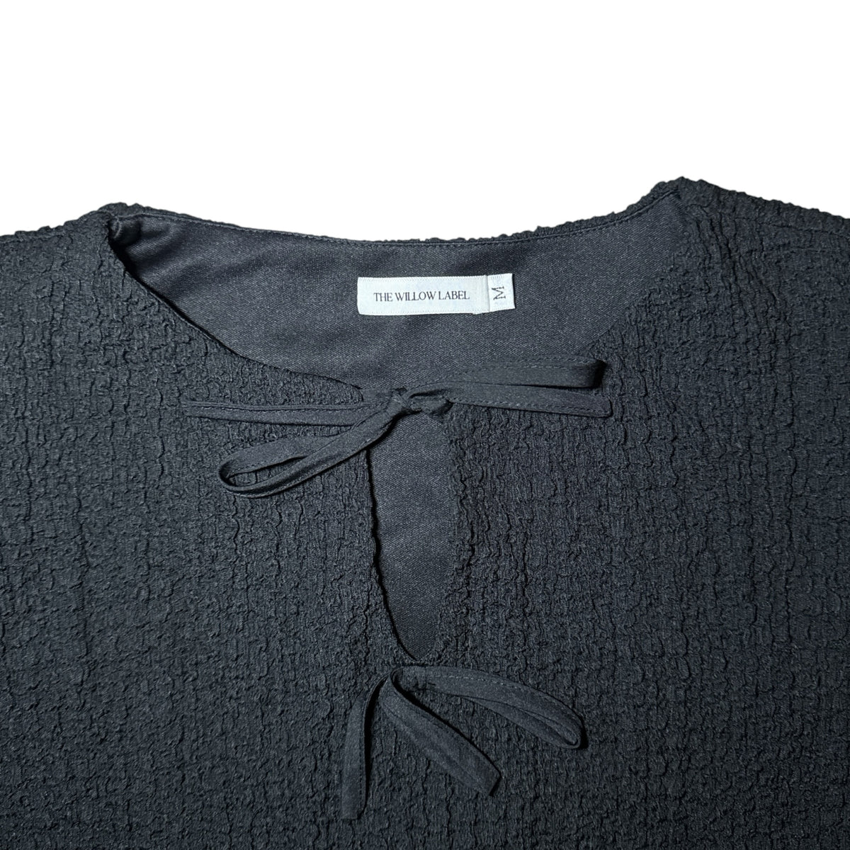 Gemstoresg black textured peplum blouse by THE WILLOW LABEL featuring a tie-front neckline detail.